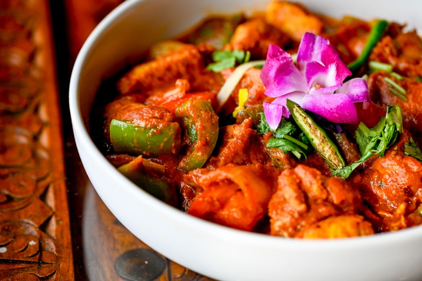 Chicken jalfrezi with bell peppers and fresh herbs in a white bowl