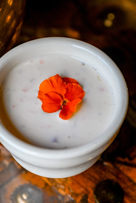House raita in a stone bowl garnished with a marigold