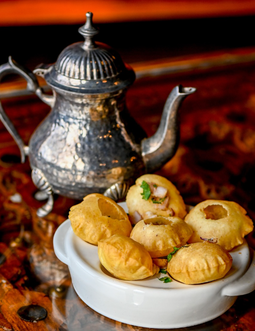 Pani puri shells with an antique silver kettle of tamarind water